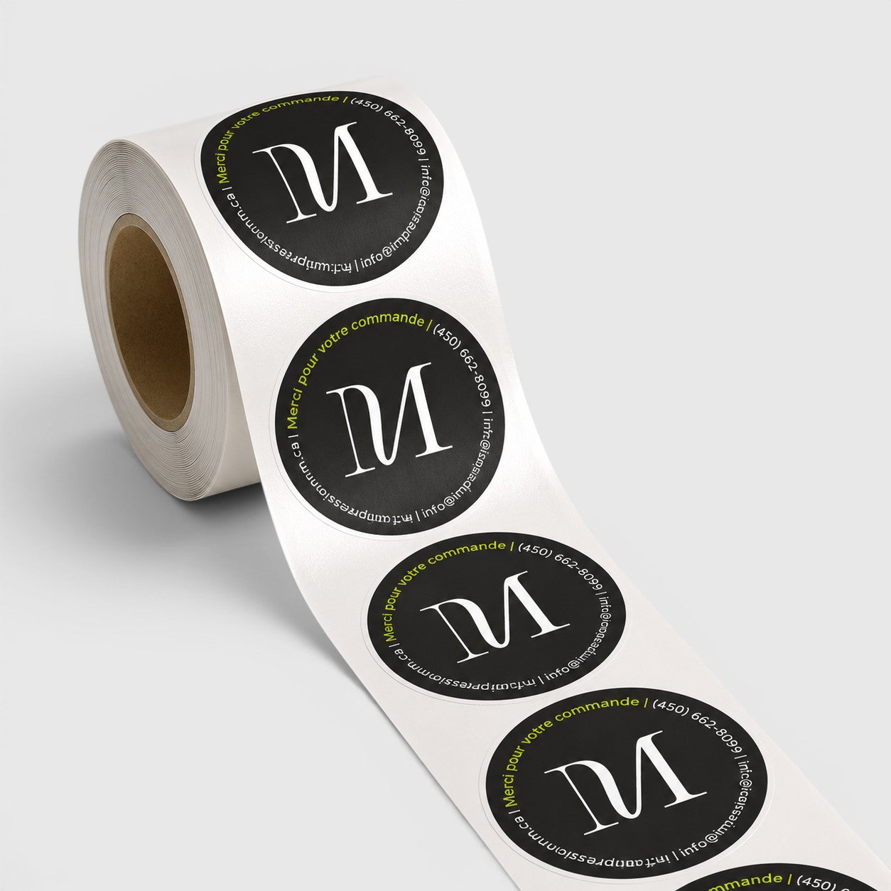 Impression M round labels on a roll featuring a black circular design with white logo and green text border